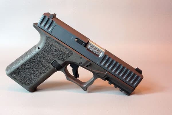 Sniper grey slide with deep front serrations on a black frame, on a light background