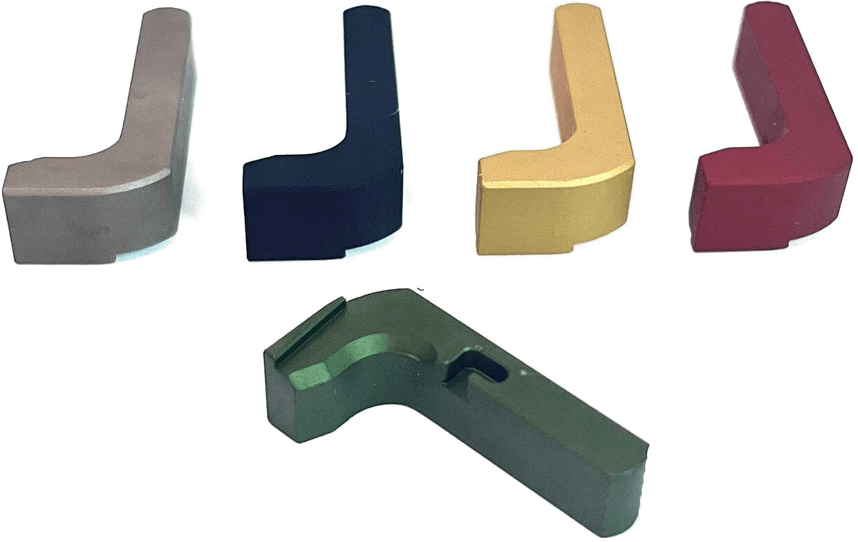 Five minimalist magazine releases in grey, navy, gold, red and green Cerakote, lined up on white