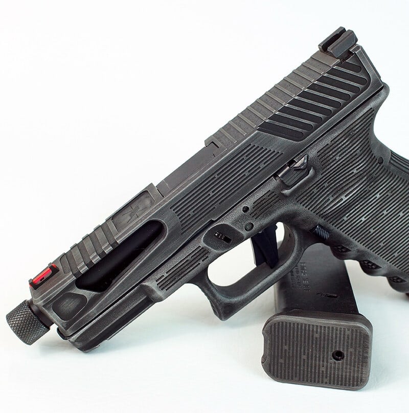 NMF slide in graphite black with stepped front and rear serrations, on a black Glock 19 frame against white
