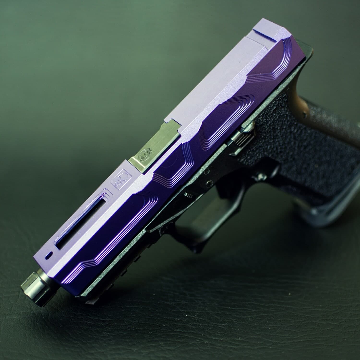 Roswell slide in violet Cerakote with green accents, mounted on a stippled black Glock 19 frame against a dark green backdrop