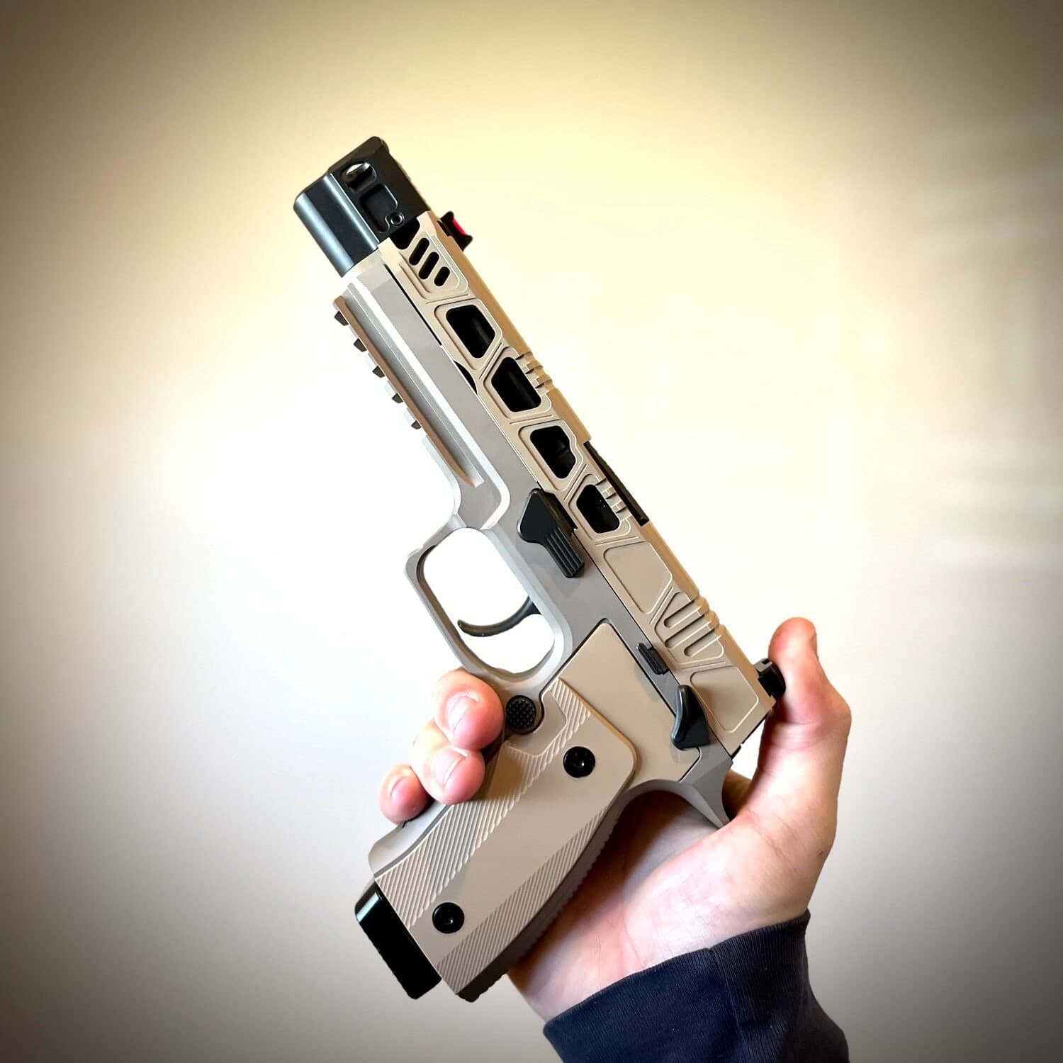 Hand holding a Sig P320 with the Cyberpunk slide in sniper grey, open side windows and a mounted red dot